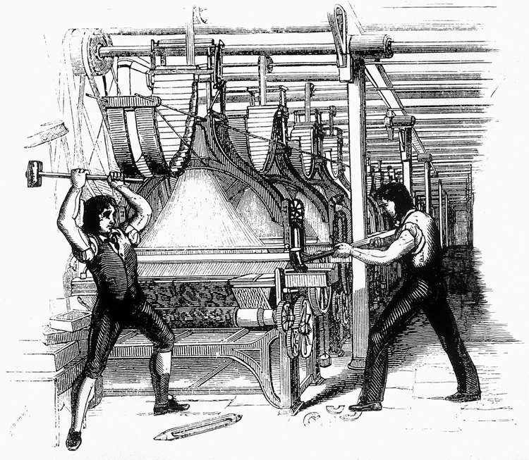 Two men destroying industrial textile machines with hammers in a factory setting.